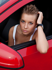 Fascinating teen girl undressing and showing attractive slim body outdoors near red opel.